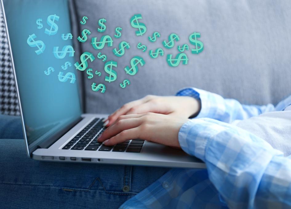 hands on laptop with dollar signs floating above